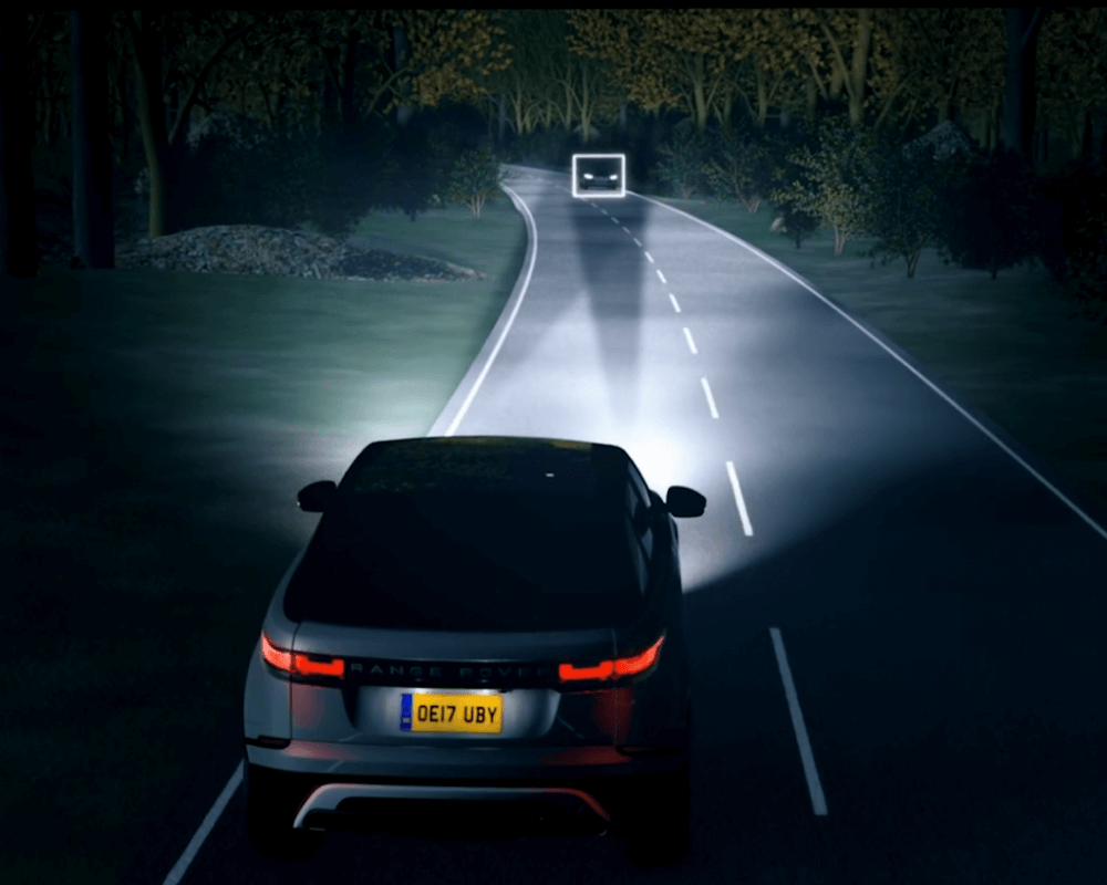 Car driving at night with headlights lighting up road with directions
