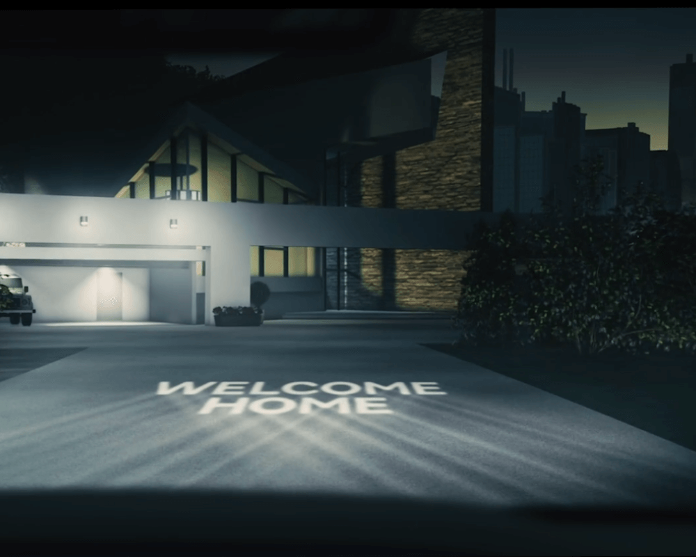 Headlights projecting welcome home onto driveway in CGI